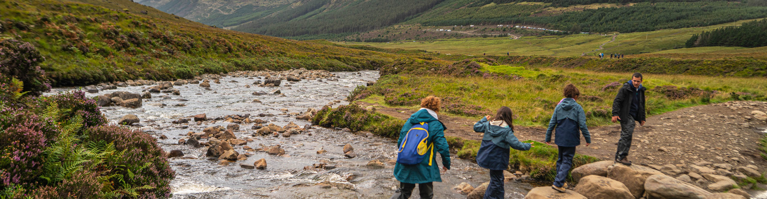 Hikers walking across a stream in the Scottish Highlands 