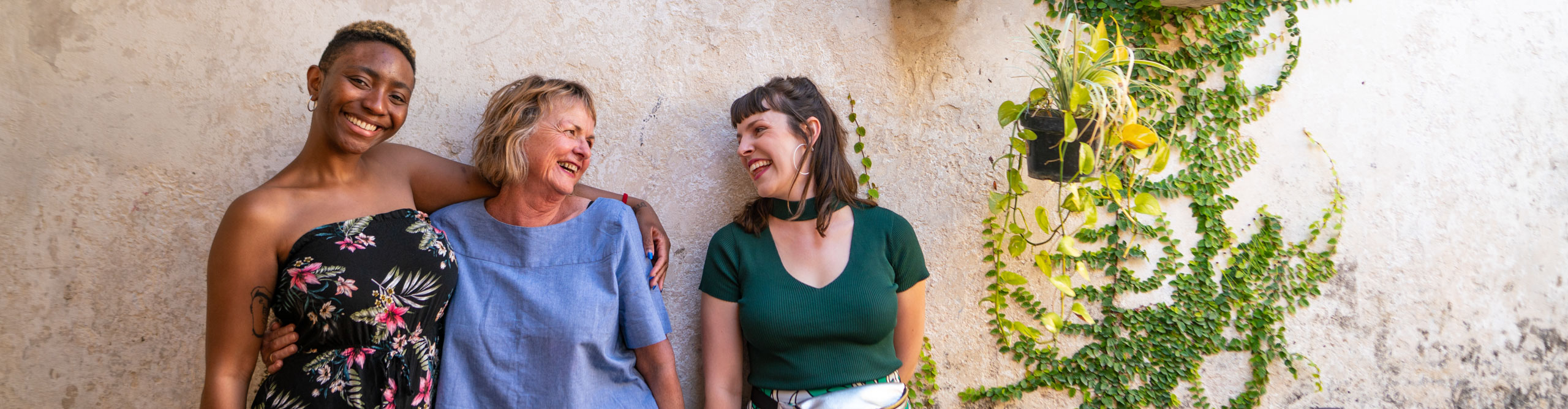 Women smiling and laughing and leaning against a wall in the sun in Mexico 