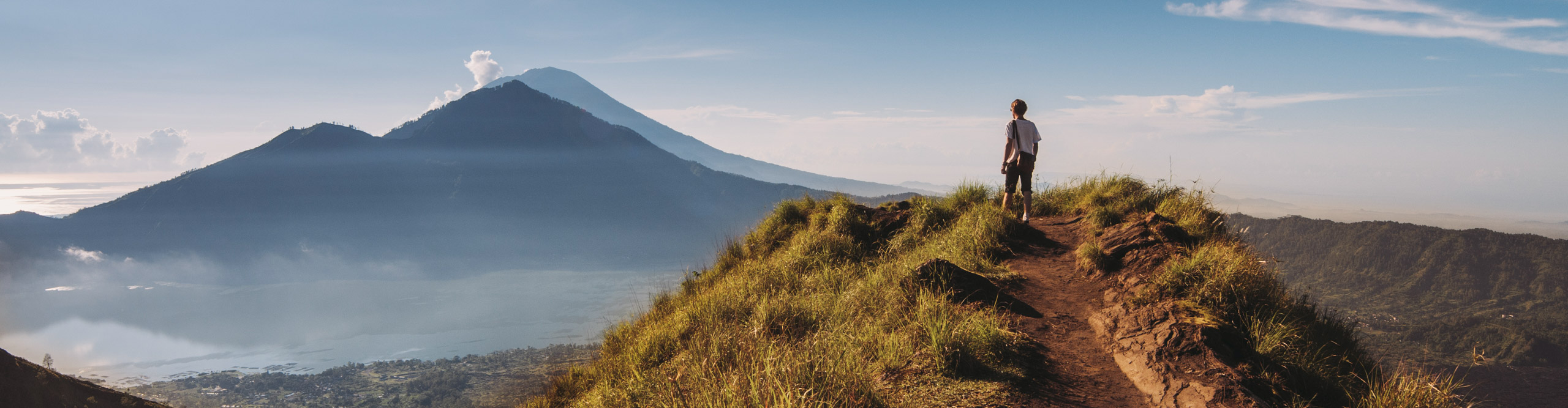 Hiker staying on top of Mount Batur, Indonesia, on a clear day at the sun is setting 