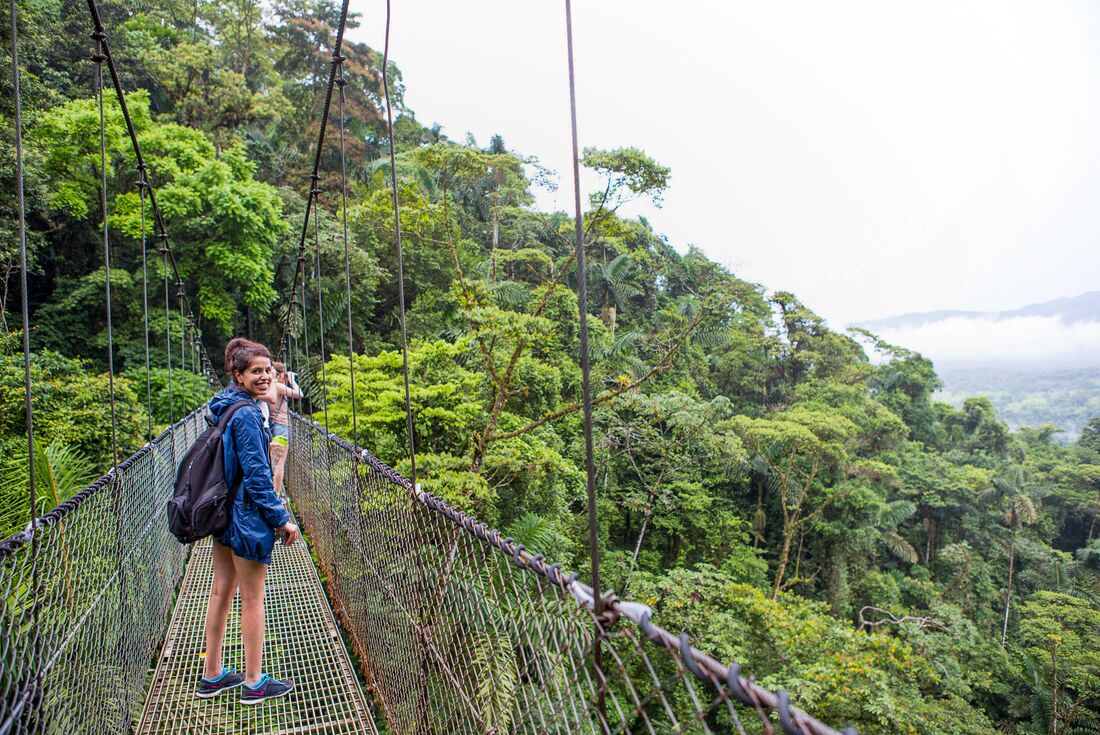 Traveller crosses the Arenal bridge amongst the tree tops in Costa Rica