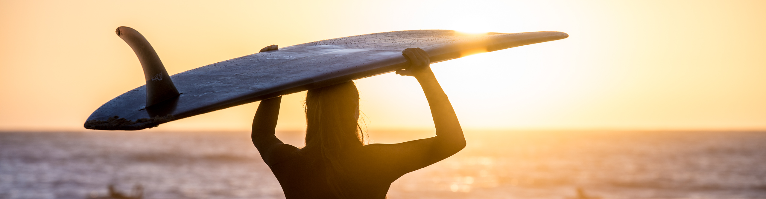 female surfer at sunrise standing on beach on the east coast of Australia