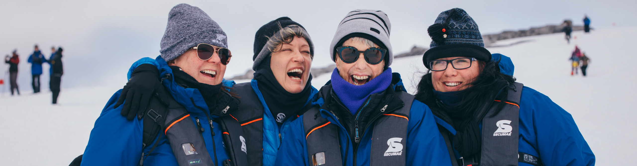 Group laughing and smiling at the camera in the snow, Antarctica