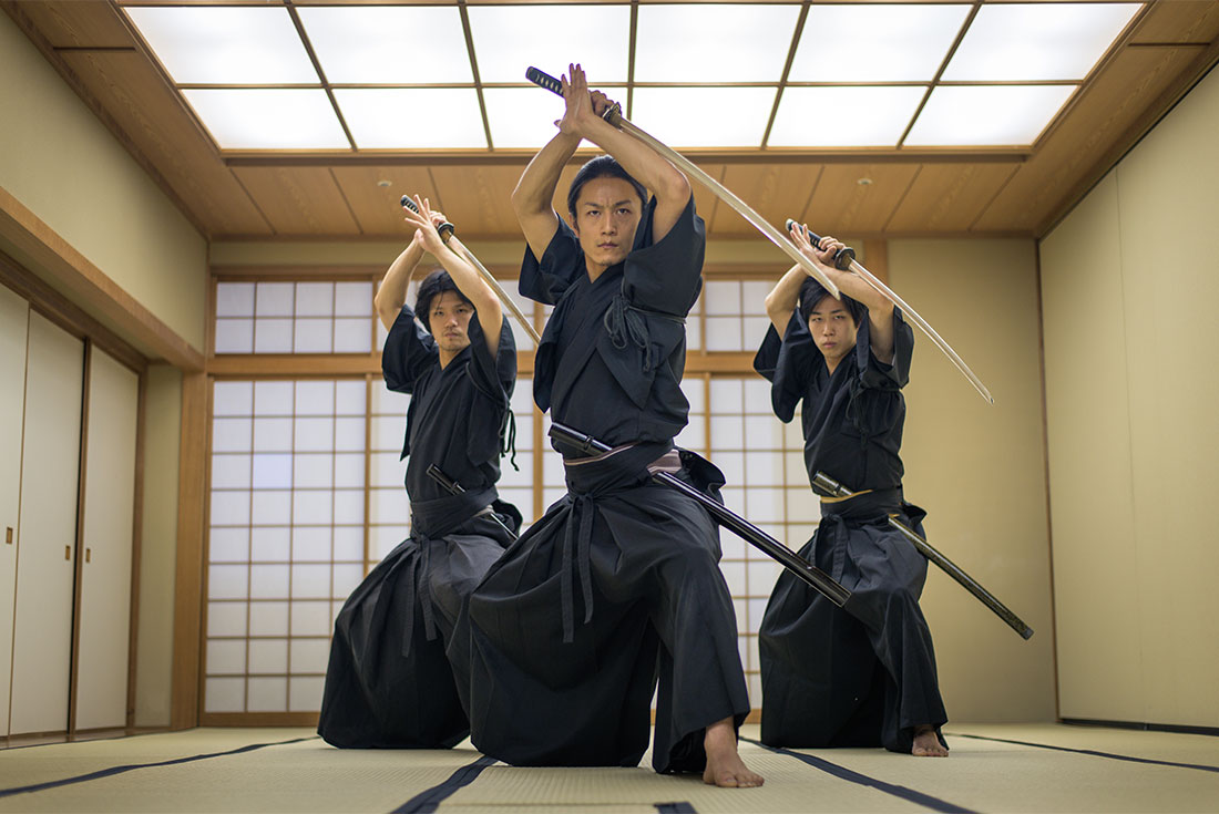 Group of practicing samurai pose with swords in a dojo in Tokyo