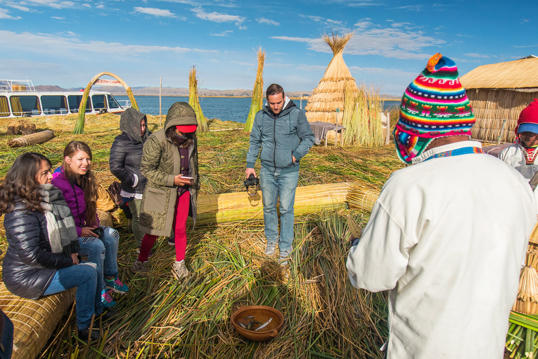 Group of travellers and locals on floating island, Lake Titicaca homestay, Peru
