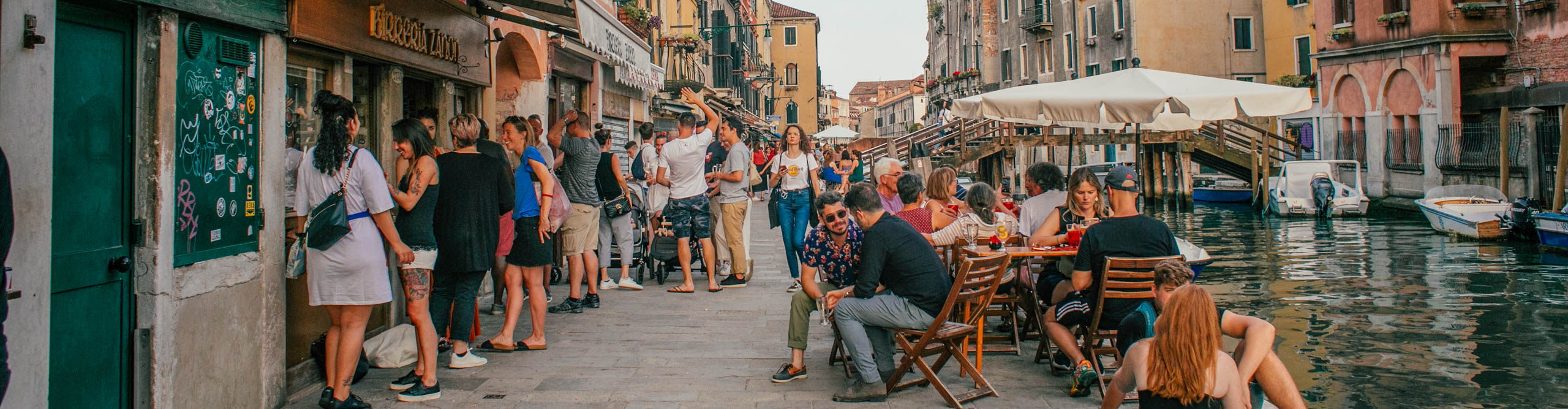 People drinking and eating in bars by the canal in Venice, Italy 