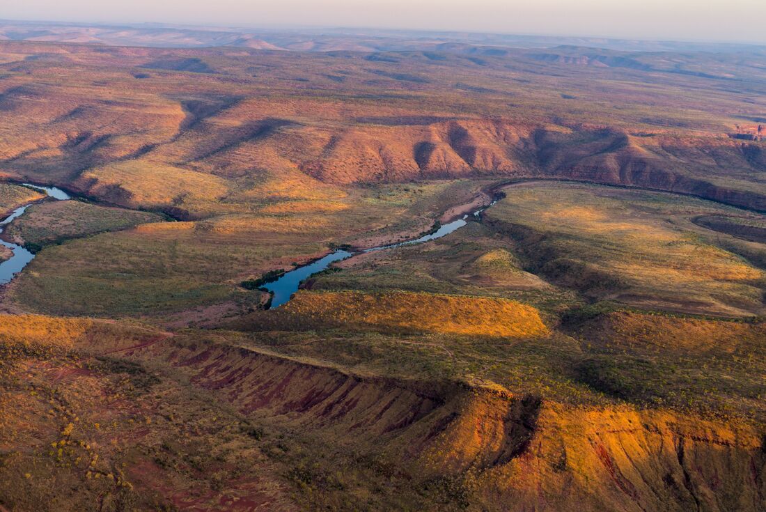 Aerial view of river running through the orange green of El Questro Wilderness Park, Western Australia