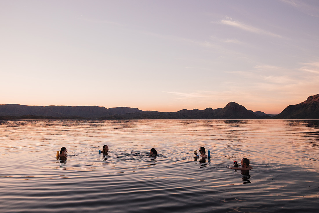 Group of travellers swimming at sunset in the Kimberley, Australia