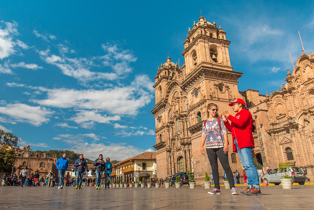 Traveller talking to Intrepid tour leader outside Cathedral, Plaza de Armas, Cusco, Peru