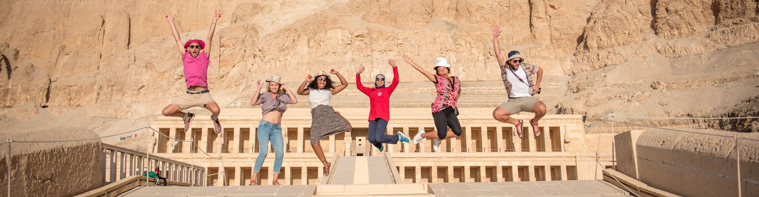 People jumping in the air in front of an ancient ruin, amongst the pyramids, Cairo., Egypt 