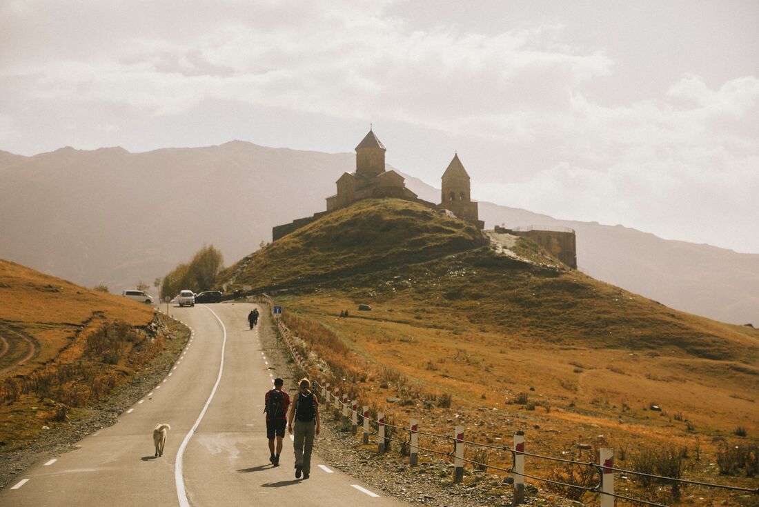 Intrepid travellers and leader walking to a monastery outside Gudauri, Georgia