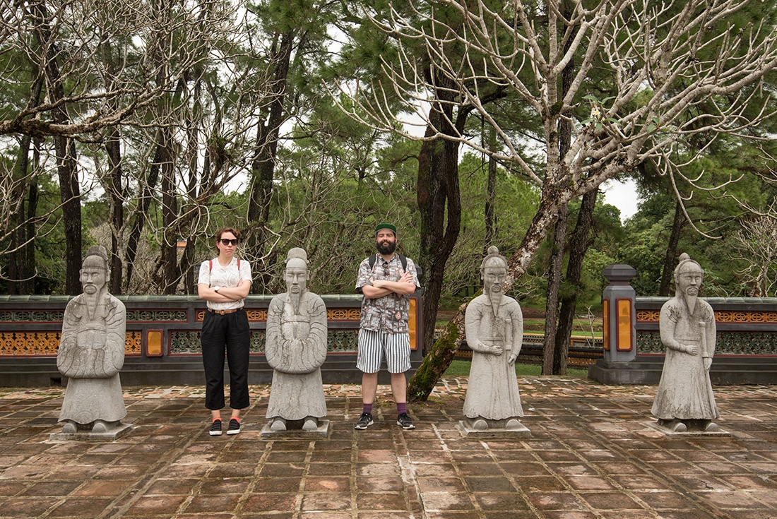 Travellers posing between stone warrior statues in the imperial citadel in Hue, Vietnam on an Intrepid Travel tour.