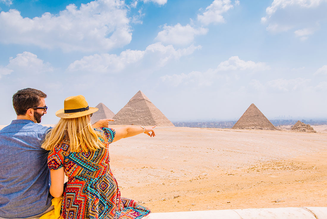 XEPE - Couple pointing and admiring the pyramids in Cairo, Egypt on a bright and sunny day