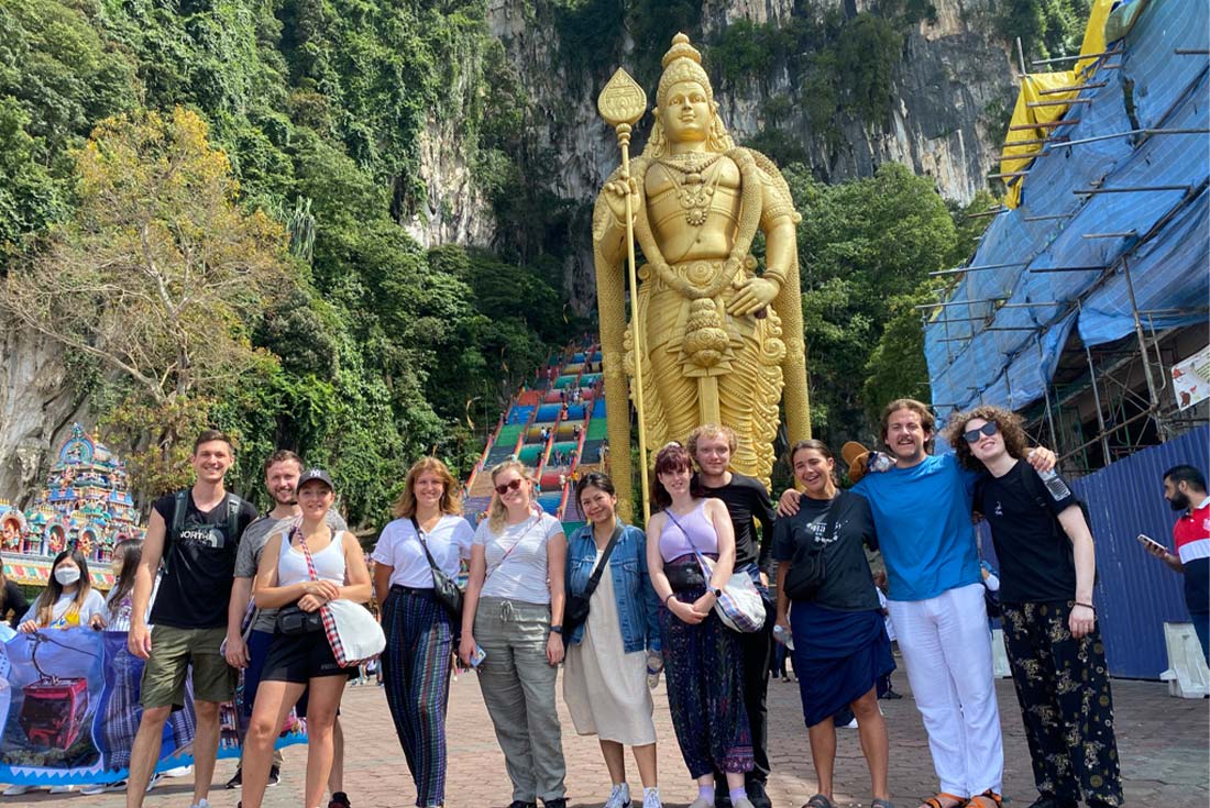 Group of travellers standing in front of colourful steps, Batu Caves, Malaysia