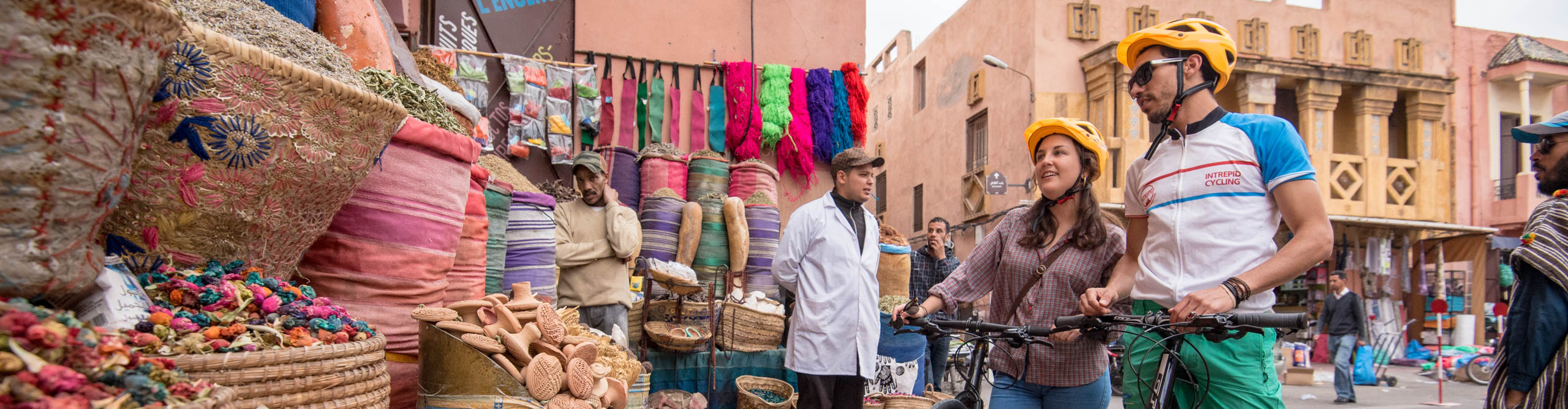 Cyclists at the markets with colourful goods in the stalls, in Marrakech, Morocco