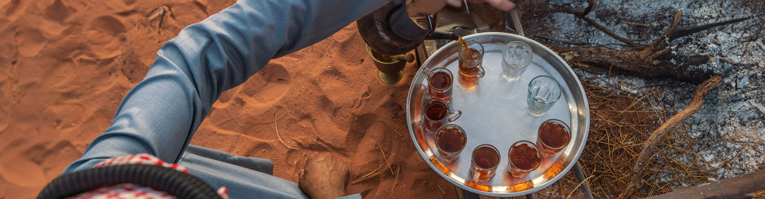 Man pouring tea into small cups in the desert for a ceremony, Jordan 