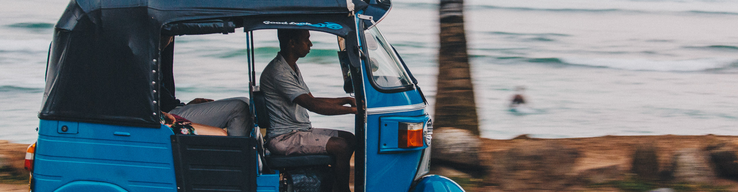 Man driving blue tuk tuk through the streets of Colombo