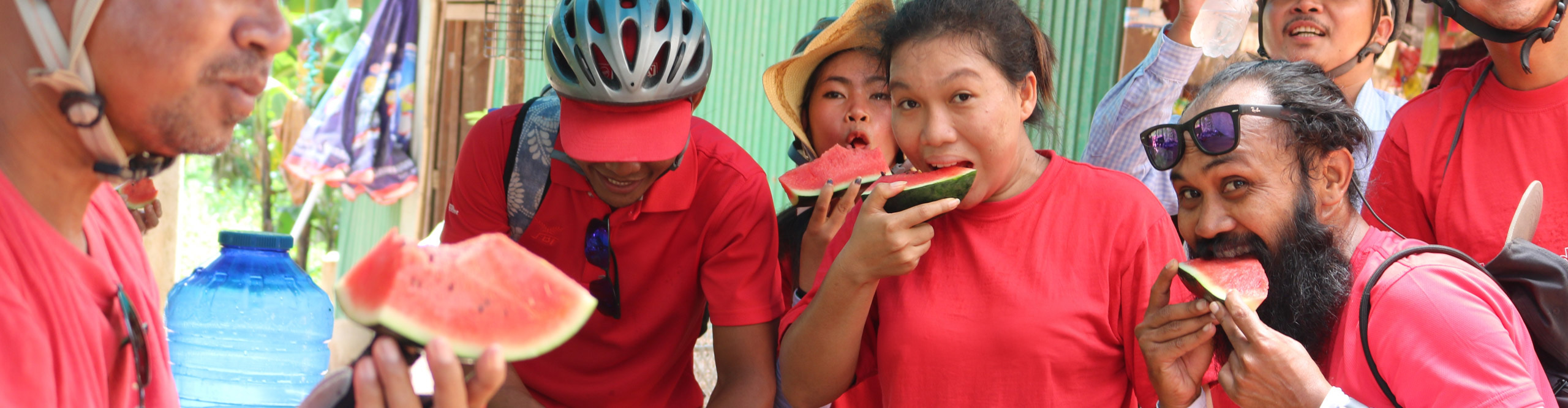 Group eating watermelon whilst on a cycling trip though Cambodia 