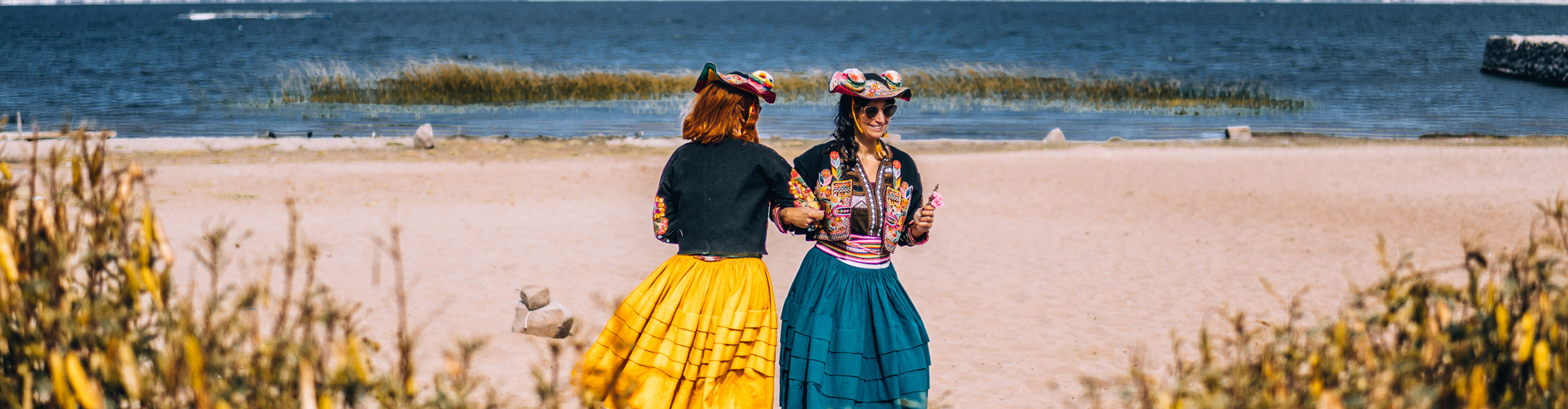 Women in traditional dress dancing on the shores of Lake Titikaka, in the sunshine, Peru 