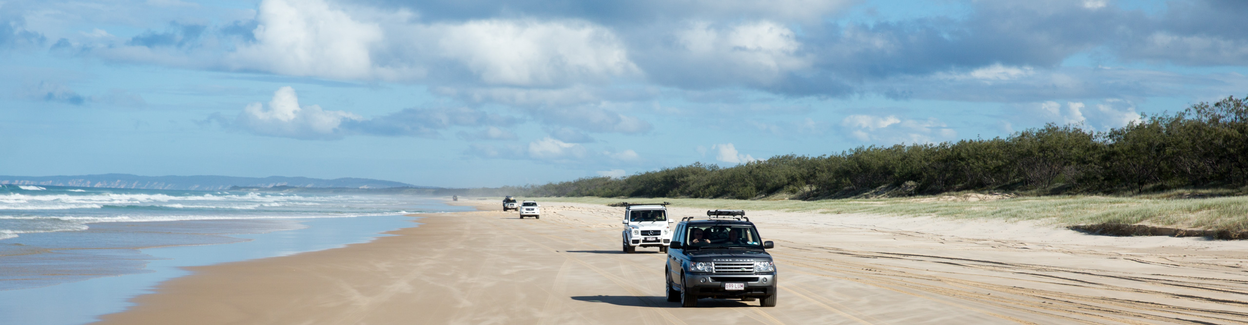 Jeeps driving along the beach on a sunny day on Fraser Island, Queensland, Australia