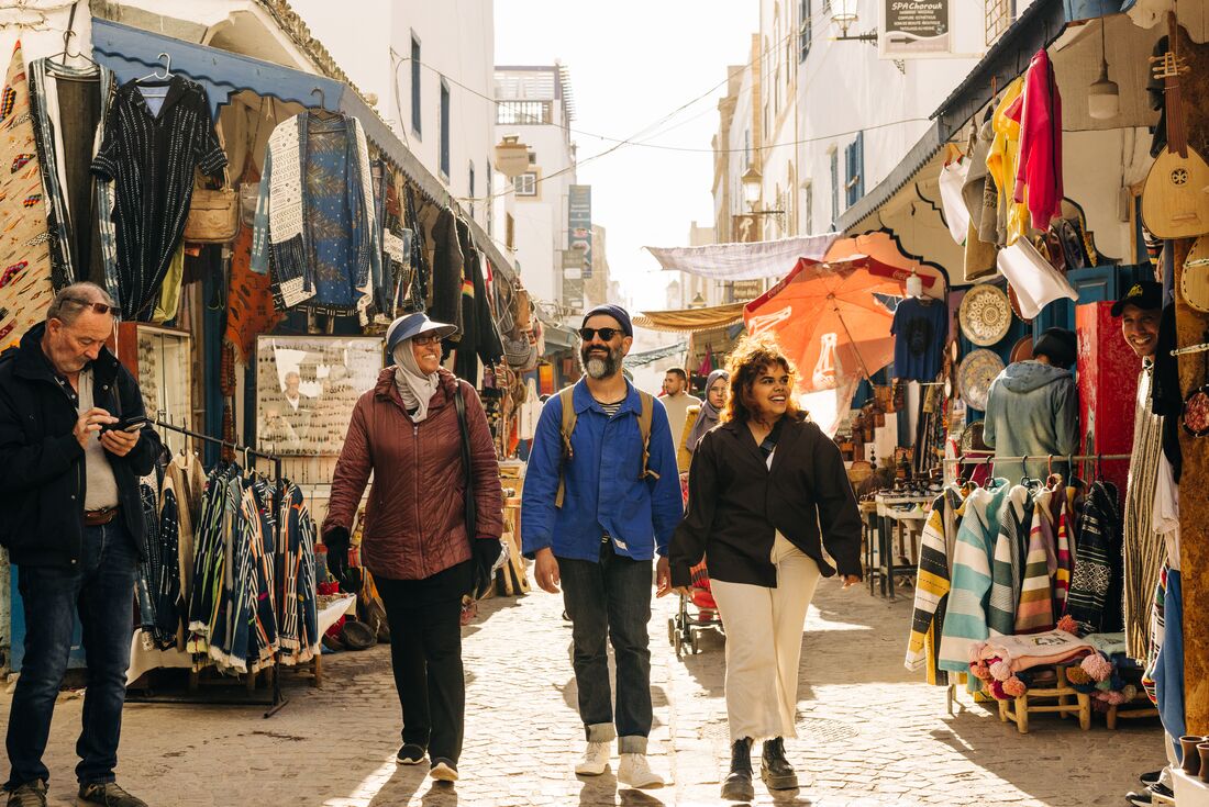 Intrepid travellers and leader walk through the streets of Essaouira in afternoon light