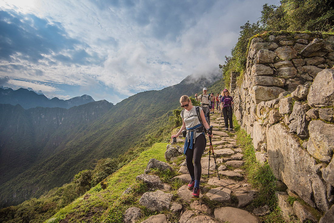 Group trek down cobbled path along Inca Trail, Machu Picchu, Peru