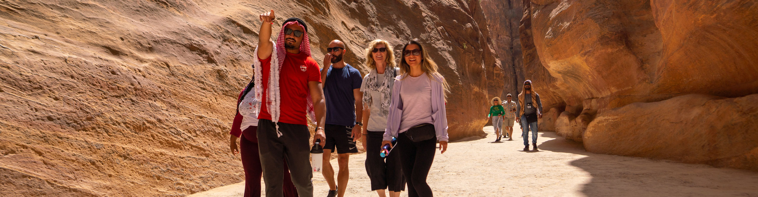 Group waling through the ancient ruins and caverns of Petra, Jordan on a sunny day 