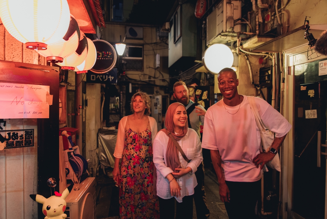 Intrepid travellers wander through Shinjuku's narrow streets with soft lantern light on either side