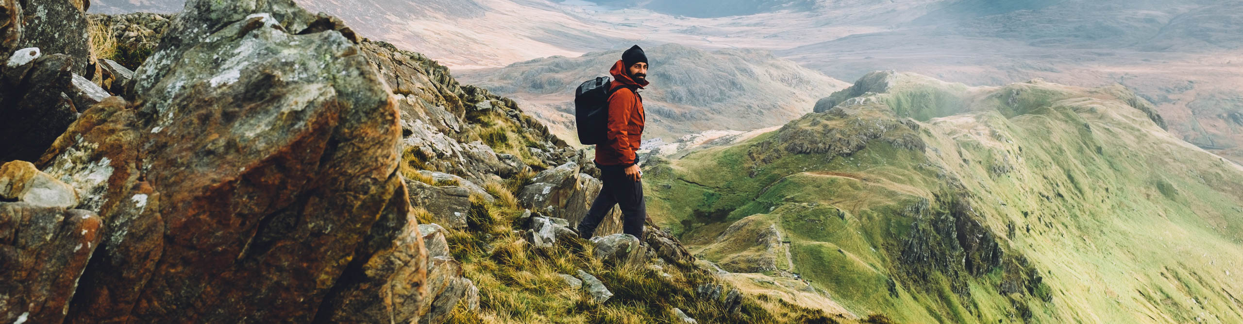 Man in red jacket hiking down the mountain in Snowdonia National Park, Wales, United Kingdom
