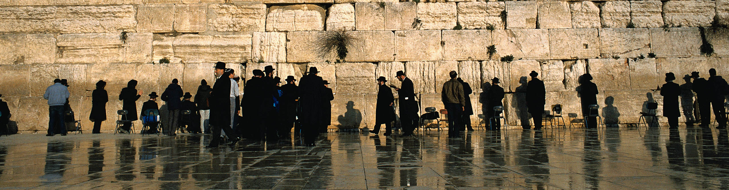 Jewish men standing in front of the Wailing Wall, at the Western temple in Jerusalem 
