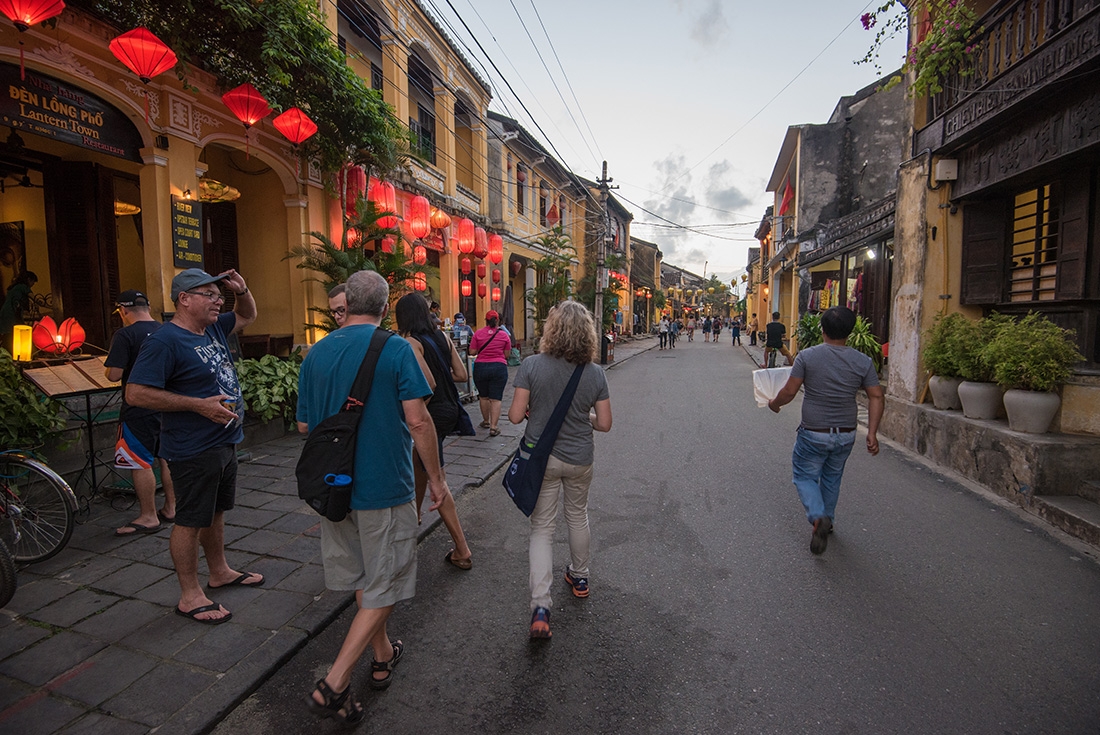 Travellers walking down a twilit street with red lanterns adorning building down the street in Hoi An, Vietnam on an Intrepid Travel tour.