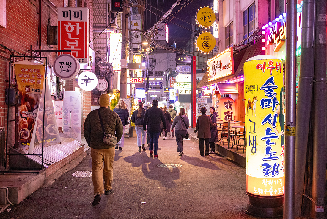 Group walking the neon lit streets of Myeongdong, Seoul, South Korea