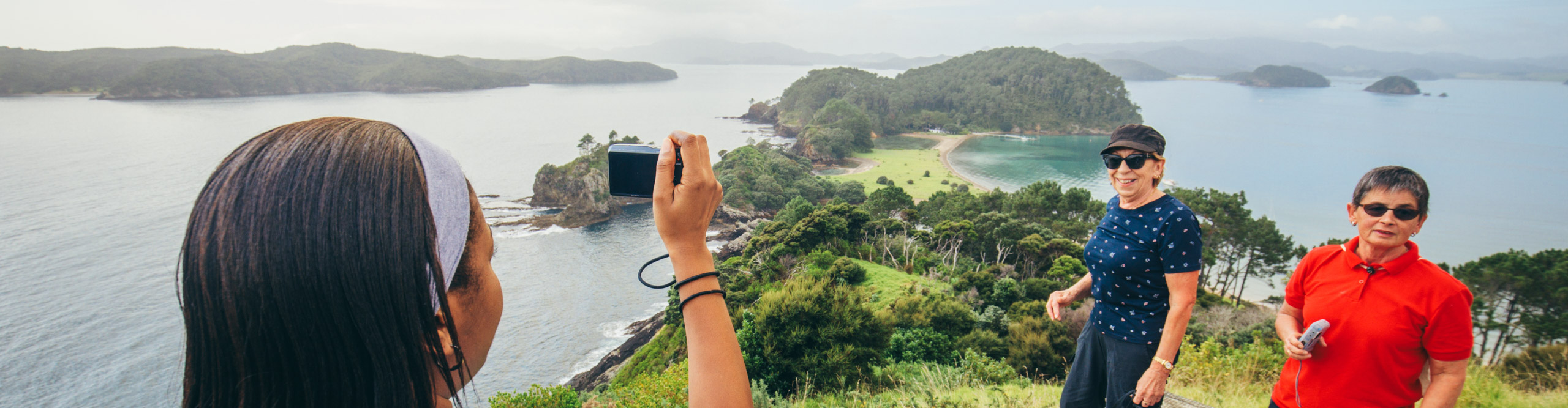 Hiker taking photos on the path down to a beach in the Bay Of Islands, New Zealand