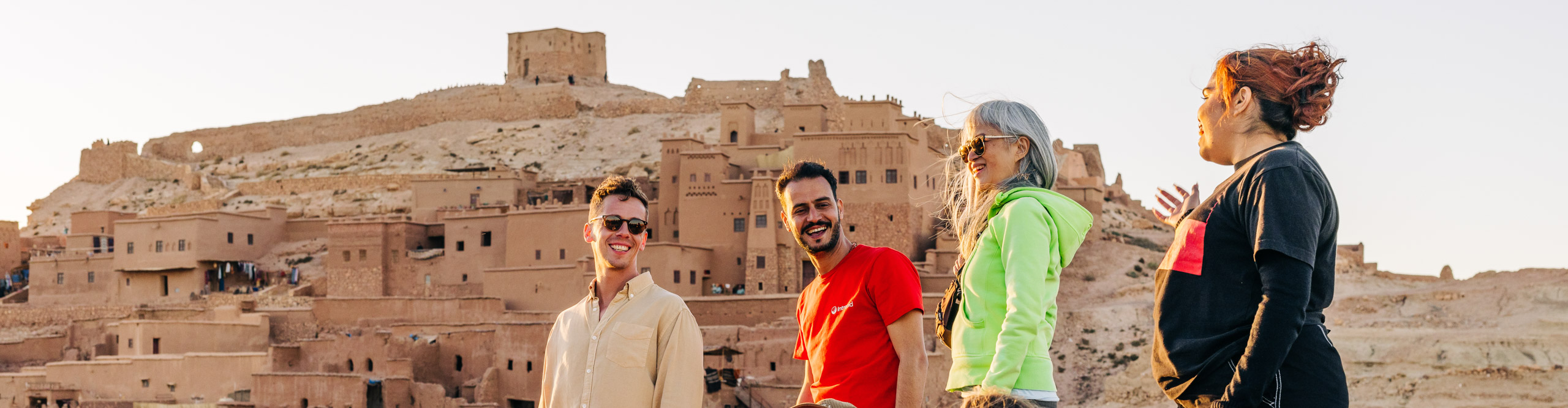 People standing and laughing at the top of a hill overlooking an ancient town in Morocco