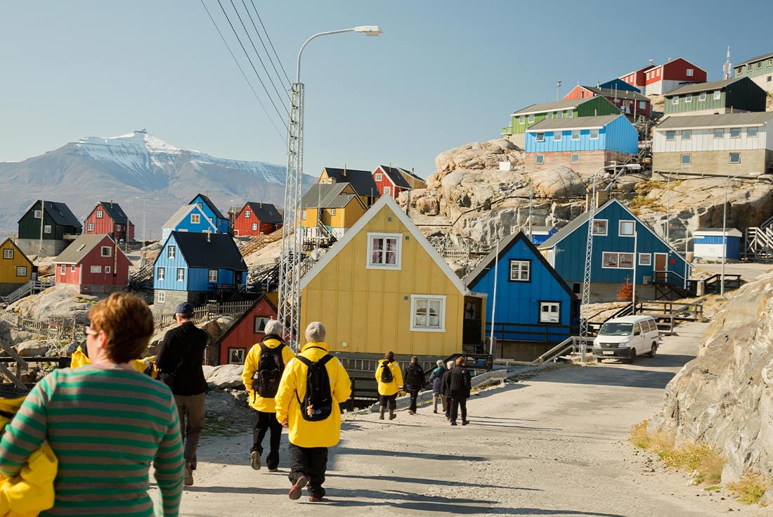 Travellers exploring colourful houses Ummannaq in West Greenland