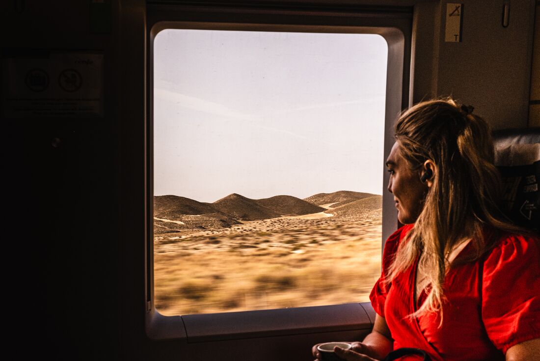 Intrepid traveller looks out train window at landscape on the way to Seville, Spain