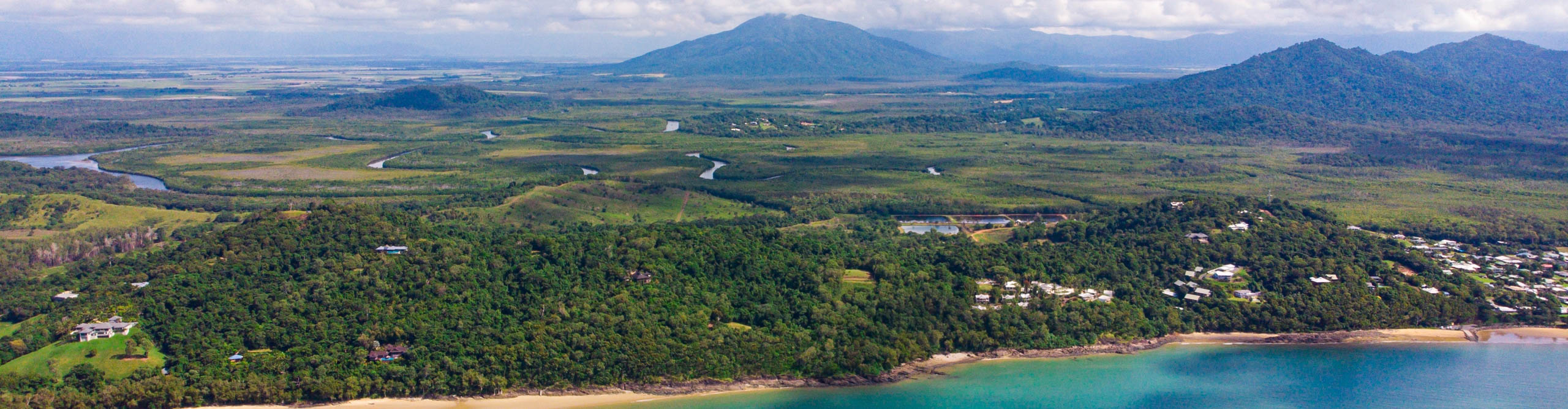 Aerial view of Mission beach on a cloudy day, with mountains in the distance, Queensland, Australia