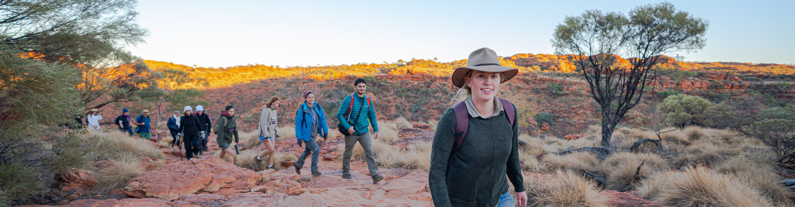Group hiking through the outback at Kings Canyon during sunset
