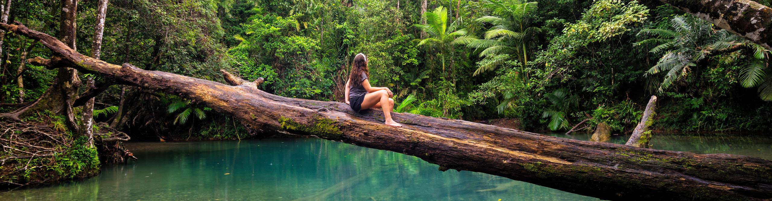 Woman sitting on log over the river in Queensland, Australia 