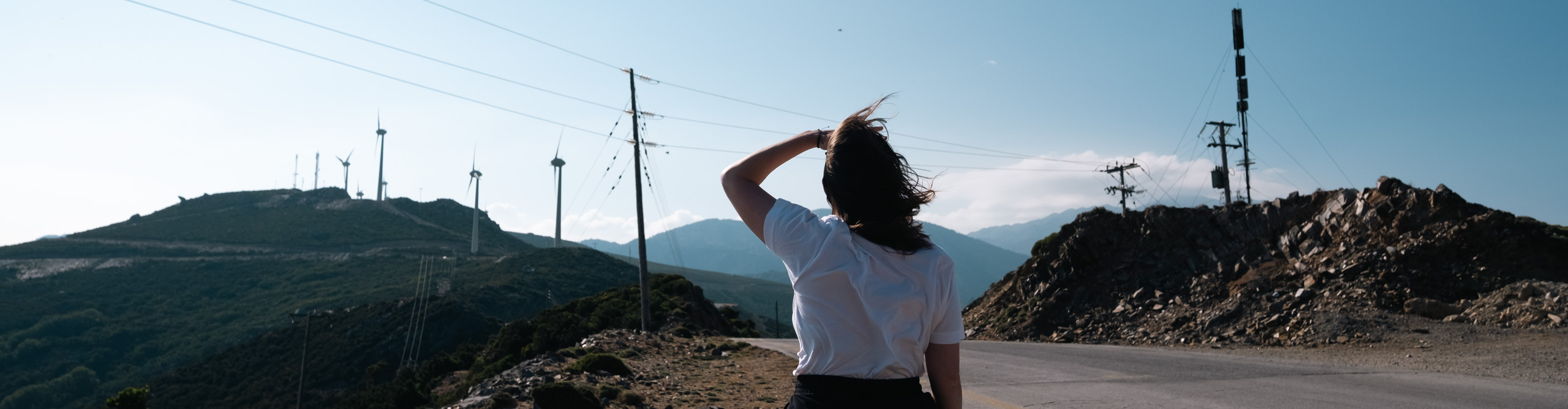 Woman looking at mountain with power lines in front in Greece