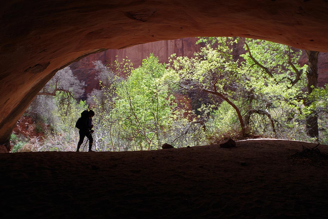 Traveller under dark arch in Coyote Gulch, Utah, U.S.A.