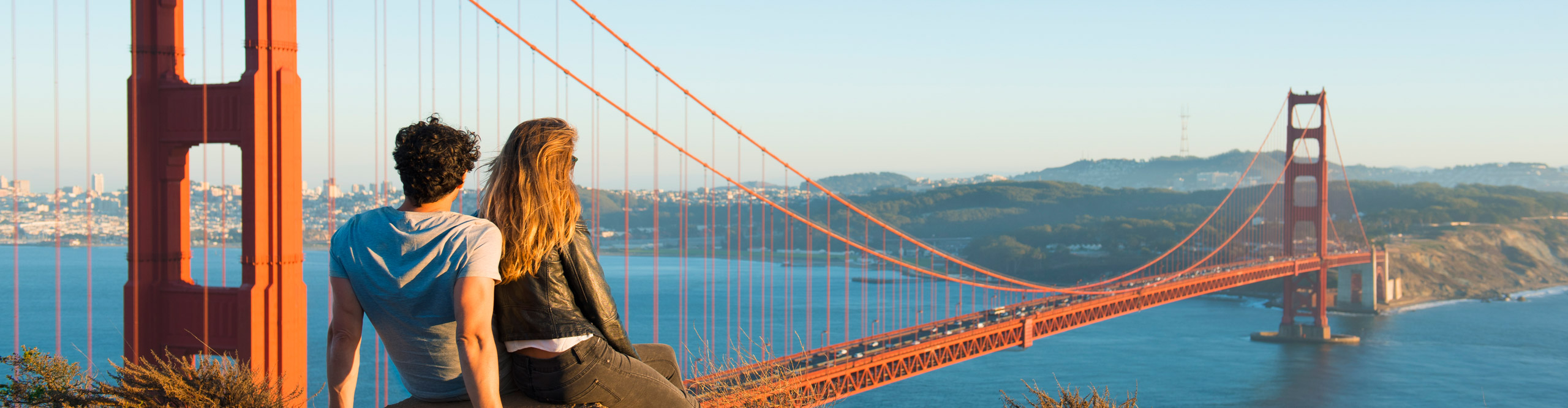 Couple admiring Golden Gate Bridge, on the hill during sunset San Francisco, California, USA