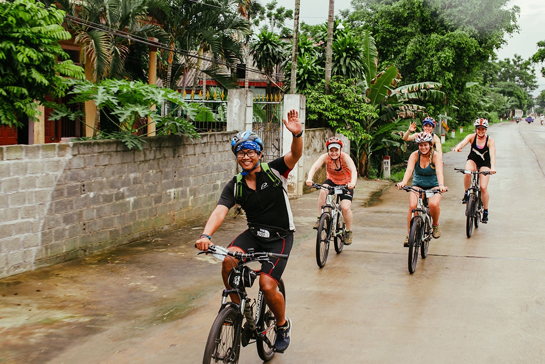 Group leader and other travellers riding through a town on an Intrepid Travel trip in Vietnam.