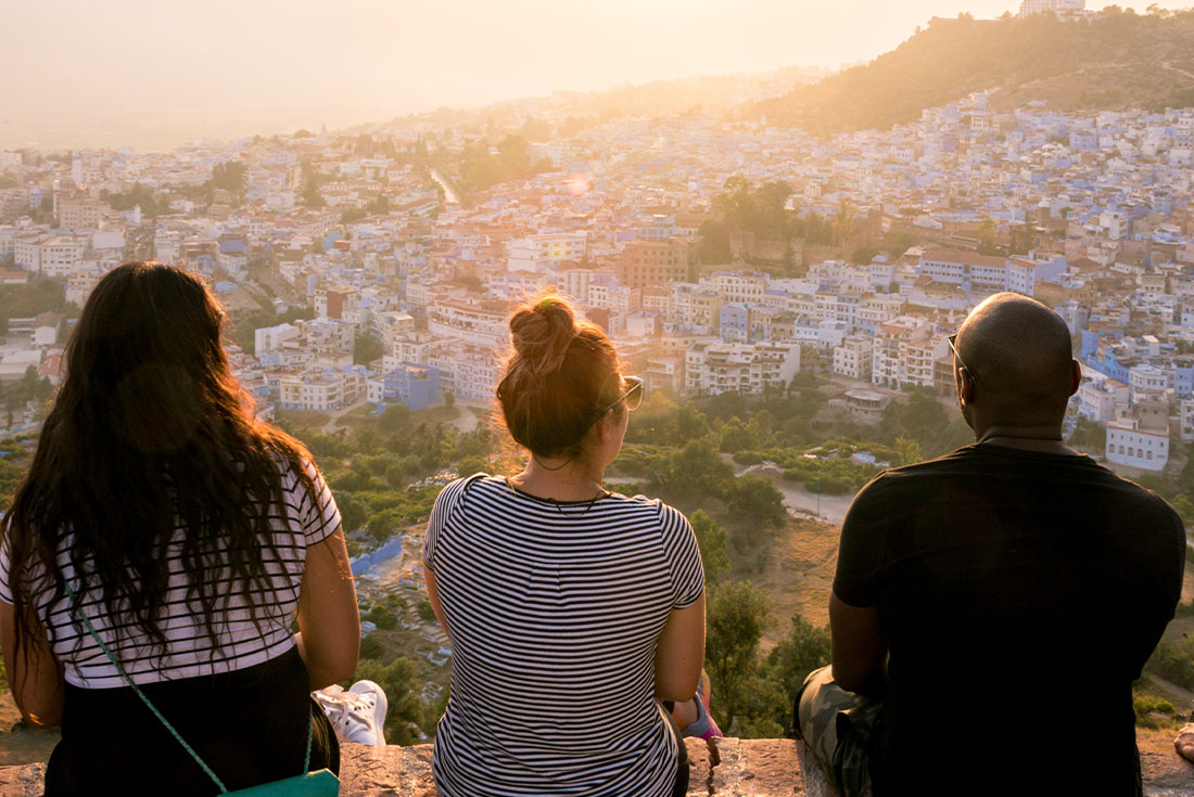 Group of travellers watching the sunset over colourful buildings in Chefchaouen, Morocco