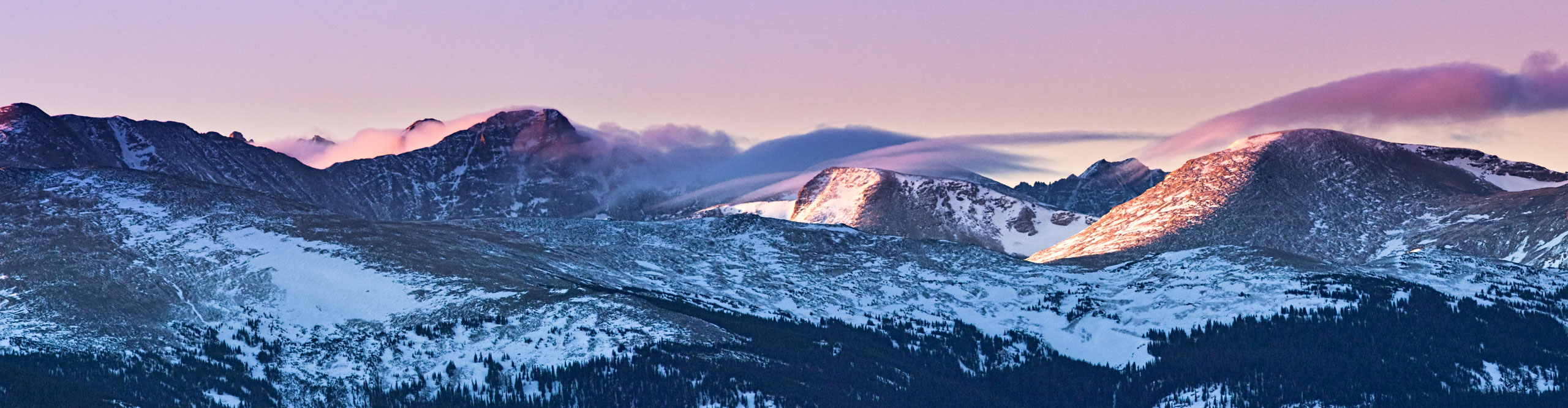 Twin Sisters in Rocky Mountain national park, at sunrise with a pink sky and fluffy clouds 