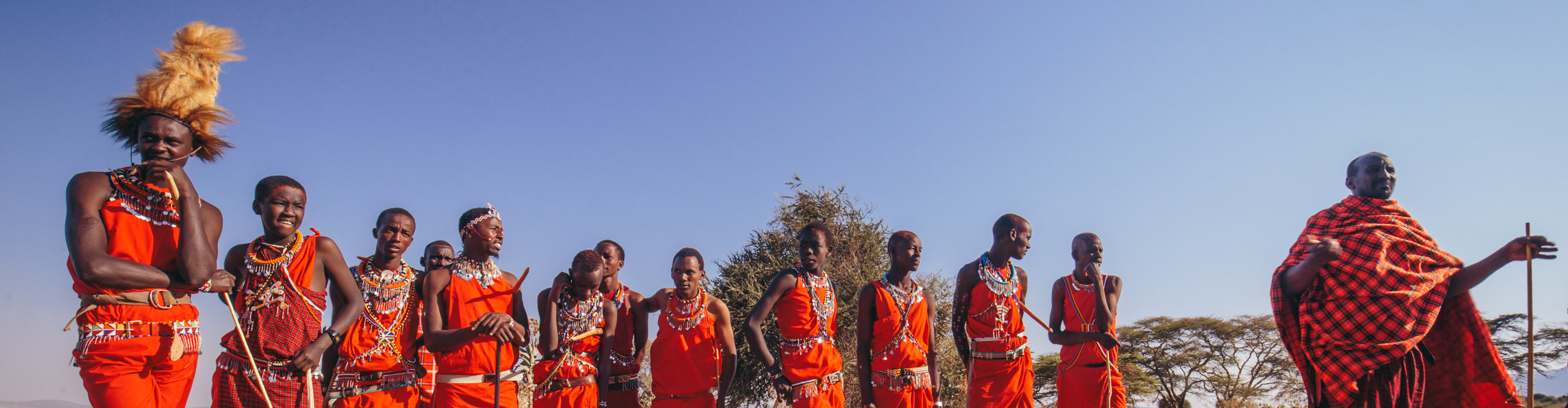 Group of Maasai tribespeople in the traditional red clothing standing in the sunshine 