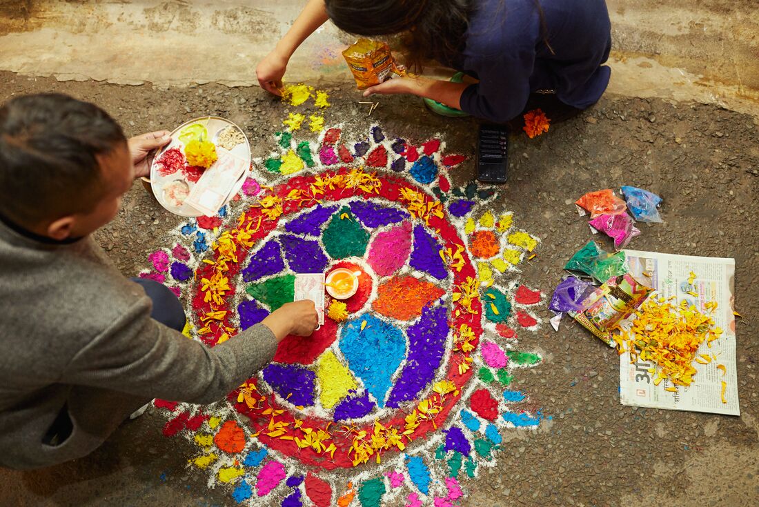 Locals creating a mandala with chalk, paint and flowerson the street in Kathmandu, Nepal