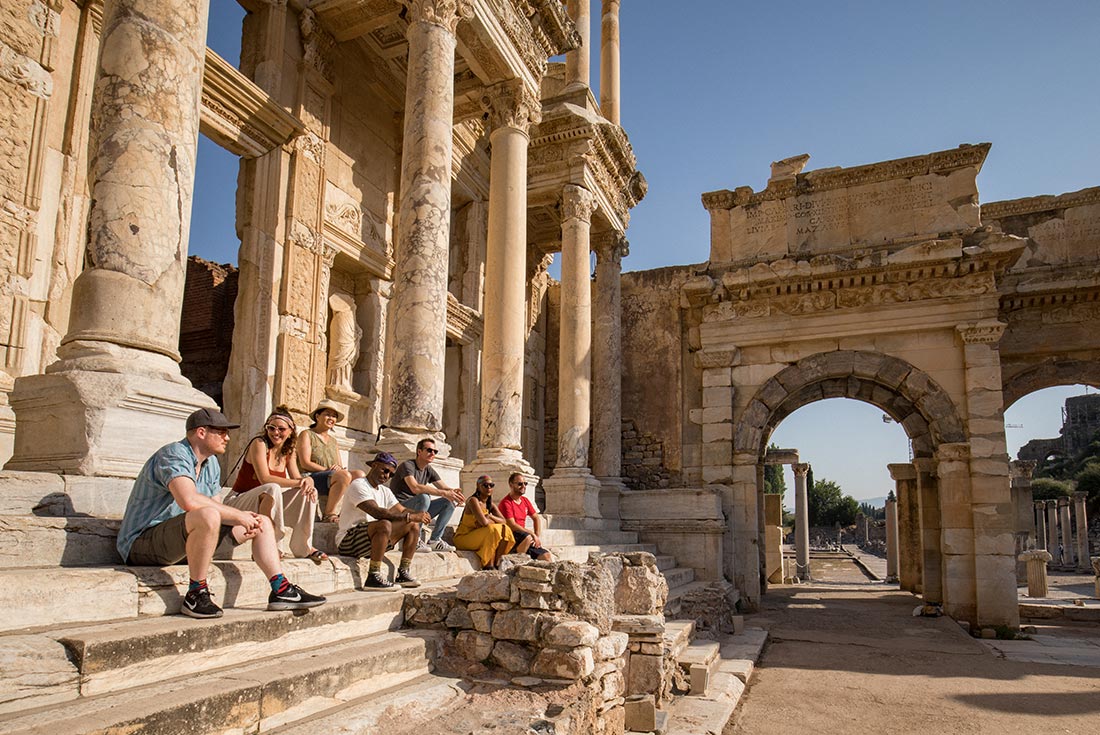 Intrepid tour group enjoy the afternoon sun in the ancient library in Ephesus Turkey