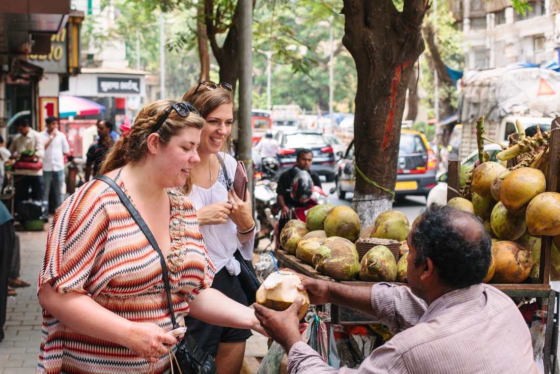 Travellers buying some fresh coconut to drink, India on an Intrepid Travel tour.