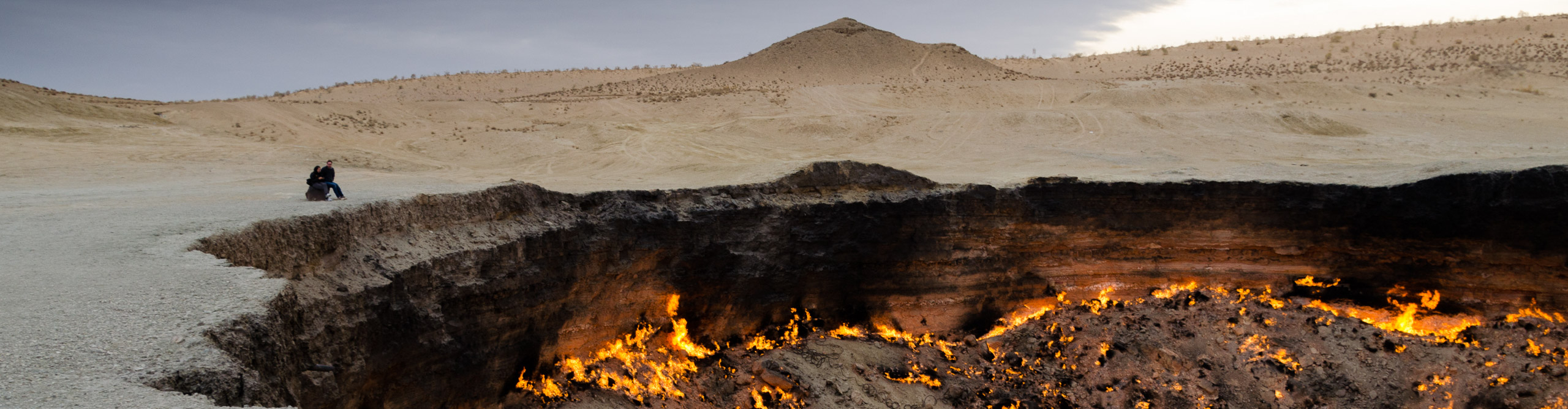 Couple looking at the Darwaza gas crater, also known as the 'Door to Hell' in Turkmenistan
