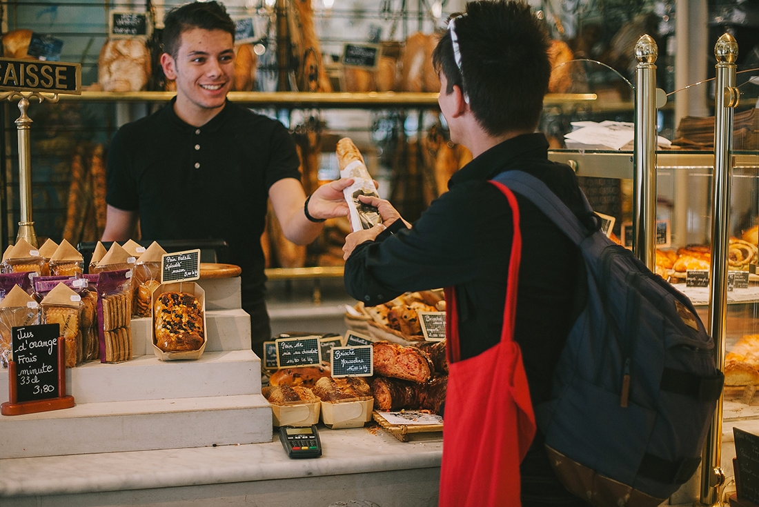 Traveller buys baguette from bakery, Paris, France